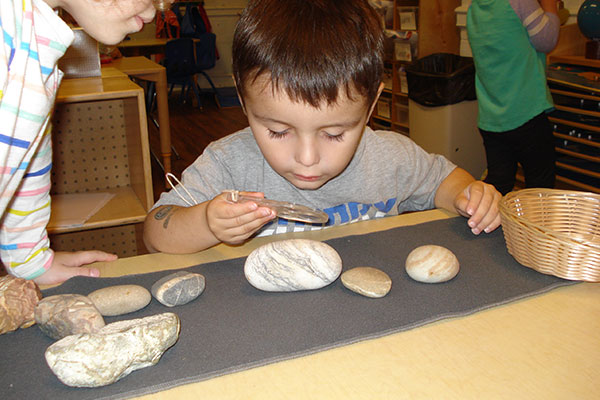 boy looking at rocks through magnifying glass